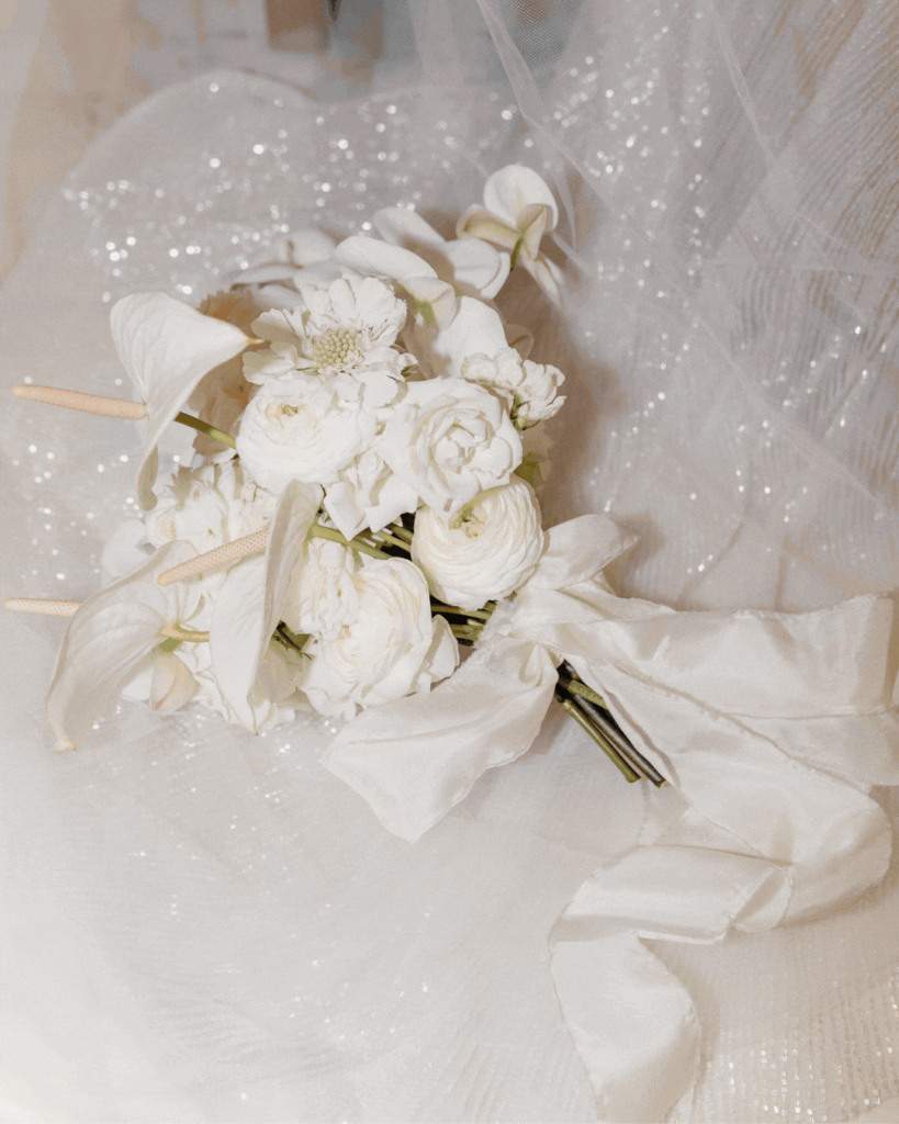 Bridal bouquet with ribbon against silk wedding dress and veil at San Francisco City Hall