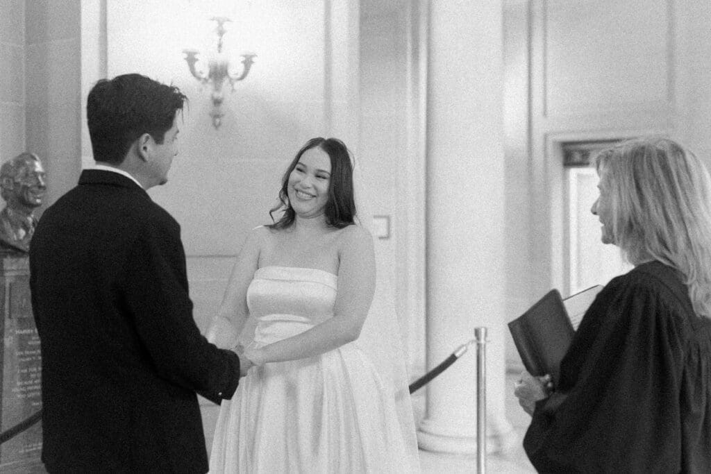 San Francisco City Hall rotunda ceremony with couple holding hands and officiant during civil wedding